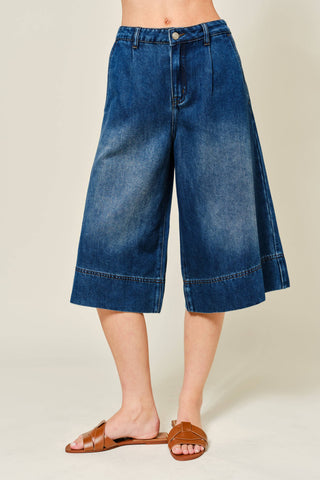 Blue denim culottes worn by a person on a beige background