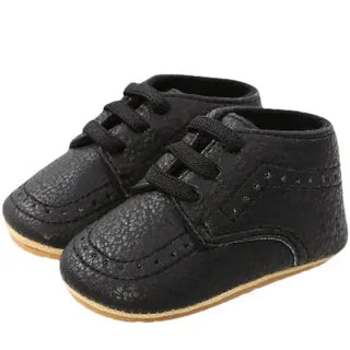 Pair of black baby shoes with laces on a white background