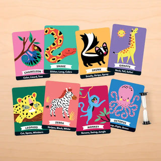 A set of colorful animal-themed educational cards arranged on a light wood surface, with an hourglass to the right. The cards feature illustrated animals and labels such as Chameleon, Snake, Skunk, Giraffe, Leopard, Zebra, Monkey, and Octopus.