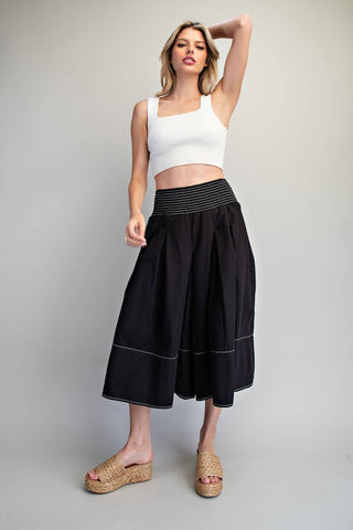 Woman wearing a white top and black skirt on a gray background
