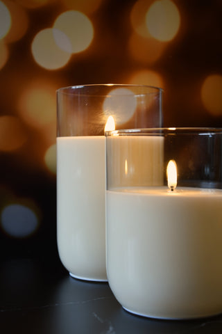 Two lit candles in glass holders with a blurred bokeh background
