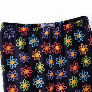 Close-up of a pair of dark navy pants featuring a colorful pattern of daisy flowers in red, orange, yellow, green, blue, and purple, with an elastic waistband.