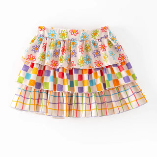 A tiered ruffle skirt with a colorful floral print on the top layer, a multicolor checkered band in the middle, and a plaid pattern on the bottom, shown against a plain white background.