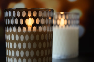 Two lit candles in decorative holders with a blurred background
