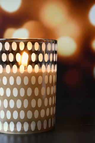 Candle in a polka dot holder with a blurred warm background