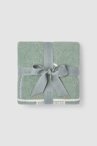 Green textured blanket with a gray ribbon on a light gray background