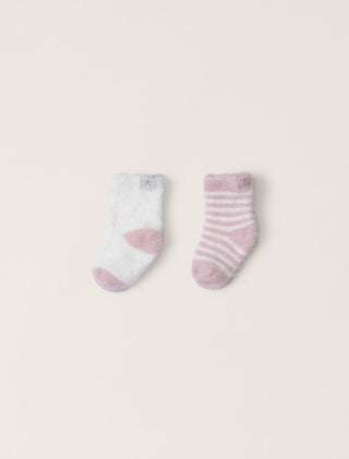 Two baby socks with pink and white patterns on a light beige background