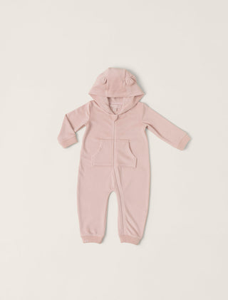 Pink baby onesie with a hood on a light beige background