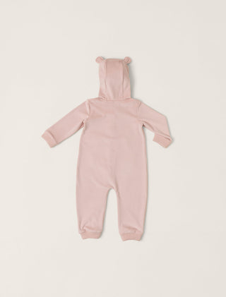 Pink baby onesie with bear ears on a light pink background