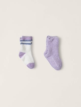 Two pairs of socks, one white with purple accents and the other solid purple, on a light beige background.