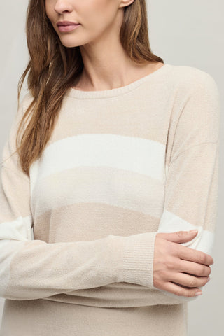 Woman wearing a beige and white sweater against a plain background