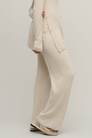 Person wearing a beige ribbed outfit with wide-leg pants on a plain background
