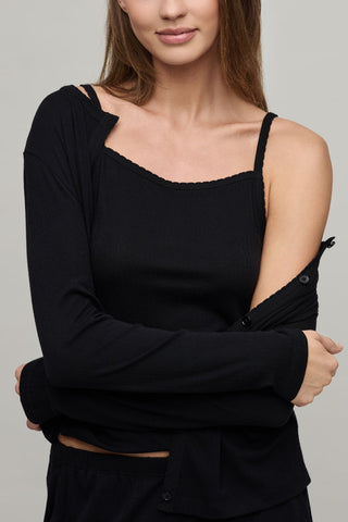 Woman wearing a black long-sleeve top with thin straps on a gray background