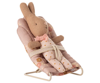 Stuffed rabbit toy in a pink cradle on a white background