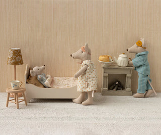 Miniature scene with toy mice in a room setting, including a bed, table, and lamp.