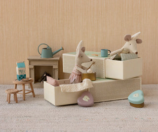 Miniature dollhouse scene with toy animals and furniture on a neutral background