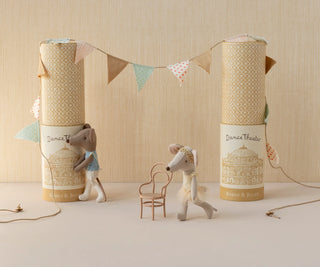 Two stuffed animal toys with decorative boxes and a banner on a neutral background