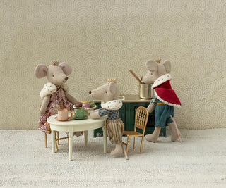 Three toy mice in a room with a patterned wallpaper.