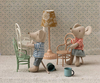 Two toy mice in a miniature room with furniture and decor.