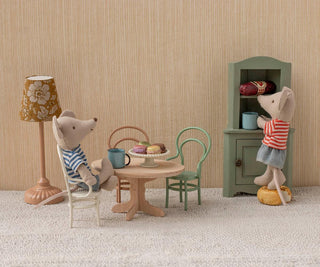 Miniature scene with toy mice around a table in a room with striped wallpaper.