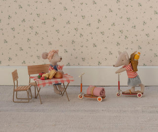 Two toy mice with a small table and chairs on a patterned floor.