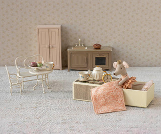 Miniature dollhouse scene with furniture and decorative items on a textured surface.