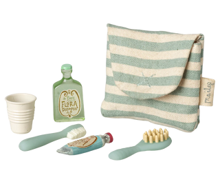 Set of children's dental care items including a cup, toothbrush, and toothpaste with a striped pouch on a white background.