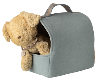 Teddy bear peeking out from a gray pet carrier on a white background