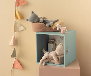 Children's room with a teal cube shelf holding stuffed animals against a beige wall.