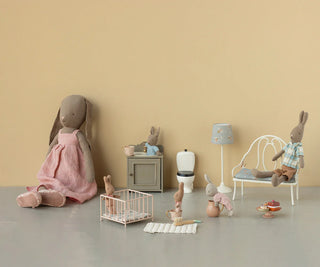 Playroom with stuffed animals and toys arranged on a plain floor against a beige wall.