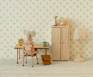 Children's room with floral wallpaper, desk, chair, cabinet, and lamp.