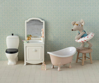 Miniature bathroom set with toilet, sink, bathtub, and decorative elements on a patterned wall background.
