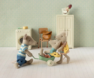 Toy mice in a miniature room with a washing machine and chair.