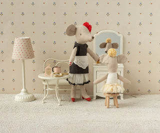 Two toy mice in a room with a lamp, table, and mirror.