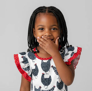 Young girl wearing a top with chicken pattern on a plain background