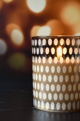 Candle in a polka dot holder with a blurred bokeh background