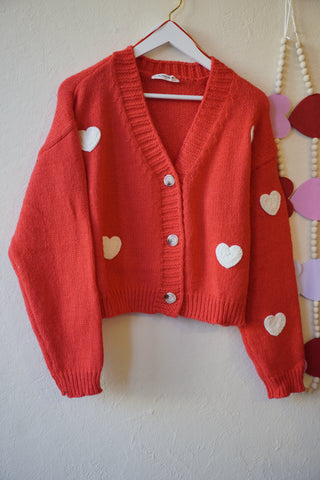 Folded red baby outfit with heart patterns on a white background