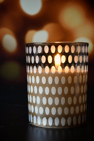 Candle in a polka dot container with a blurred warm background