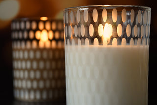 Candle in a glass holder with a patterned design, blurred background