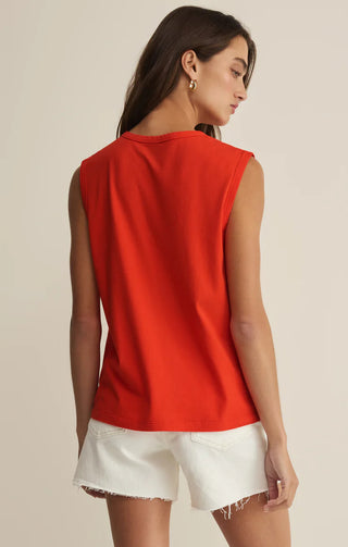 Woman wearing a red sleeveless top and white shorts on a beige background