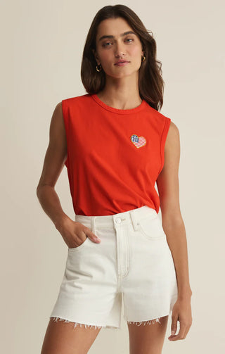 Woman wearing a red sleeveless top with a heart design and white denim skirt on a beige background