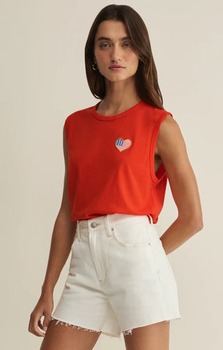 Woman wearing a red sleeveless top with a heart design and white shorts on a beige background