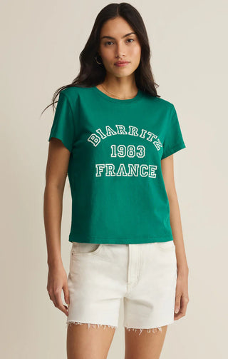 Woman wearing a green t-shirt with 'BIARRITZ 1963 FRANCE' text on a beige background