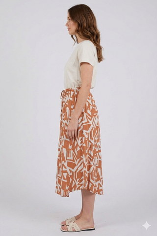 Woman wearing a white top and patterned skirt on a white background