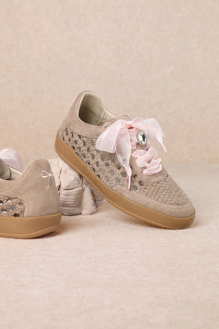 Beige sneakers with floral pattern and pink bow on a beige background