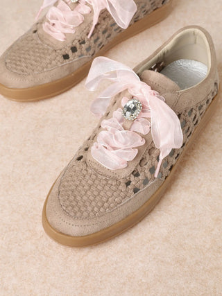 Beige sneakers with floral decorations on a beige surface