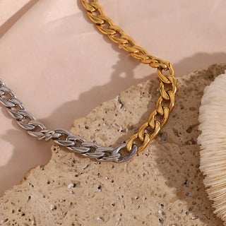 Gold and silver chain necklaces on a textured beige surface