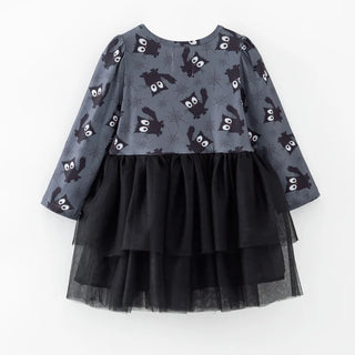 A children's long-sleeve dress with a gray printed bodice featuring black bats and spider motifs, paired with a layered black tulle skirt, shown against a plain white background.