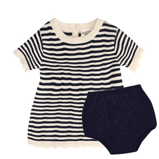 Striped baby dress with white trim and navy bloomers on a white background
