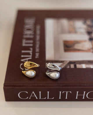 Gold and silver earrings on a book titled 'Call It Home'.